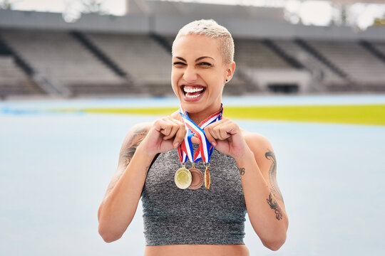 Portrait, success medals and woman athlete at stadium after winning race or sports event outdoors. Fitness, winner and female runner happy with victory, goals or target achievement on track field.