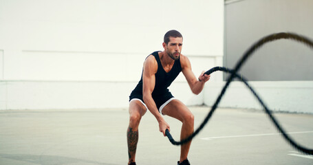 Man, fitness and battle rope training for physical exercise, workout or wellness in the outdoors....