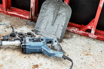 Hand-held electric vibrator for concrete pouring work with a shovel in the background. Using a...