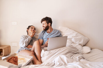 Couple laugh, pizza and movie on laptop in bed with junk food and streaming series. Eating, computer video and meal in a bedroom at home with man and woman together with bonding and online watching