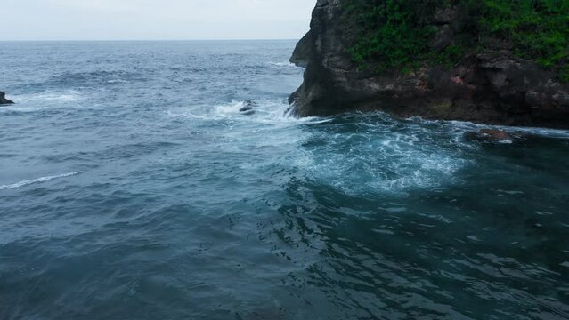 Roaring ocean waves splashing on rocky shore. Tameless sea in summer. Turquoise water washing wild beach with rocks. Peaceful lagoon on stormy day. Marine bay on gloomy day. Freshness of ocean spray.