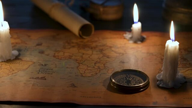 Old vintage retro compass on ancient map. Composition illuminated by candles.