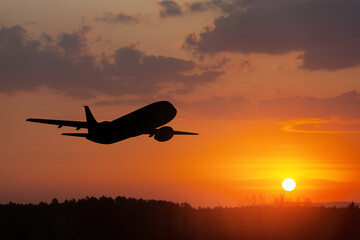 Airplane taking off at the sunset sky. Silhouette of aircraft in the sky.