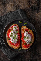 two bruschetta with tomatoes on a wooden background