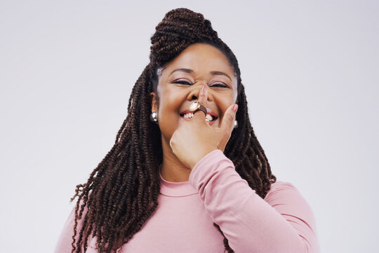 Portrait, funny face and finger on nose with a black woman in studio on a gray background looking silly or goofy. Comedy, comic and nostril with a crazy young female person joking for fun or humor