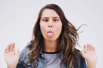 Portrait, funny face and tongue with a woman in studio on a white background looking silly or goofy. Comedy, comic or crazy and a playful young female person joking indoor for humor with an emoji