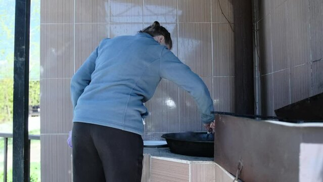 Woman cooking pilaf in cauldron on the street, lamb meat with tail fat. Video where a traditional pilaf dish is cooked. Chef uses the lamb meat that's cooked with tail fat.