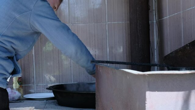 Woman cooking pilaf in cauldron on the street. Chef uses the lamb meat that's cooked with tail fat.