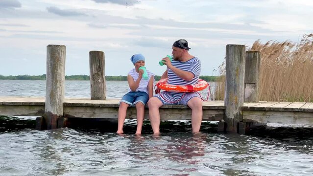 Vater und Sohn sitzen am Steg 