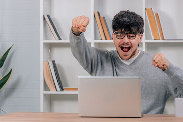 student excited with happiness with laptop at the desk
