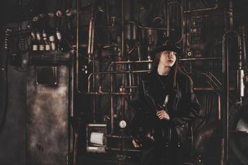 Classy teen girl model 12-13 year old in steampunk image in black leather jacket looking away. Toned image of teenage girl actress posing in industrial room. Adventure style concept. Copy text space