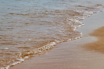 Wave with foam on the sandy beach