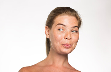 Obraz premium Pretty girl with freckles looks away with her hair tied up in front of the camera on a white background