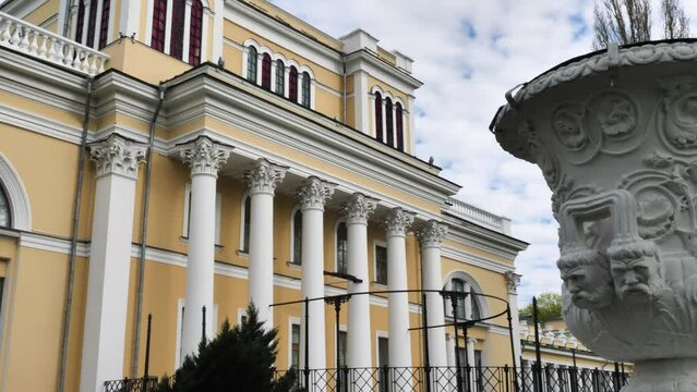 An old yellow building with columns and a small architectural form. Rumyantsev-Paskevich Palace in a city park in Gomel, Belarus. Panorama from right to left