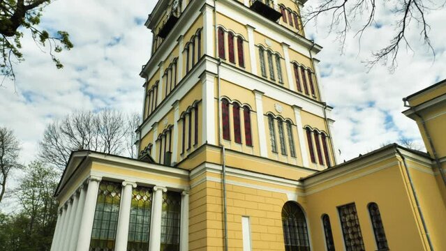 An old yellow building with a clock on a cloudy sky background. Rumyantsev-Paskevich Palace in a city park in Gomel, Belarus. Panorama from below upwards