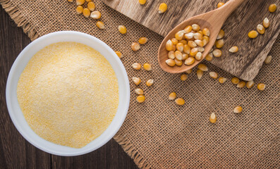 plate with cornflour , wooden spoon and corn kernels on a wooden table