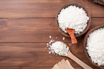 soy wax in wooden spoon on wooden background, copy space