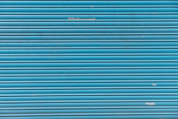 Fototapeta premium detail of a worn blue metal shutter, textured background