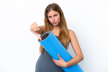 Young sport woman going to yoga classes while holding a mat showing thumb down with negative...