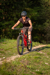 Fototapeta premium Female cyclist on her mountain bike riding through the hills on a sunny day.