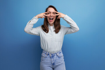 well-groomed young brunette lady dressed in a striped shirt and jeans smiling on a studio background