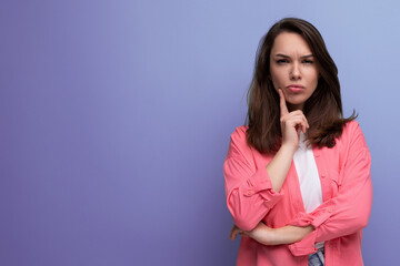 portrait of a well-groomed european young black-haired woman with shoulder-length hair in a pink shirt on a studio background with copy space