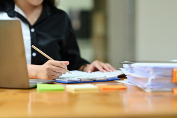 Cropped image of professional businesswoman writing business strategy, signing a contract at working desk