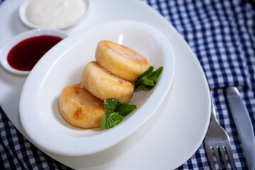 Round cottage cheese pancakes in a white plate on a blue background. Food breakfast. Healthy food.