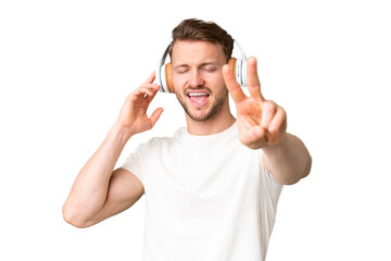 Fototapeta premium Young handsome caucasian man over isolated chroma key background listening music and singing