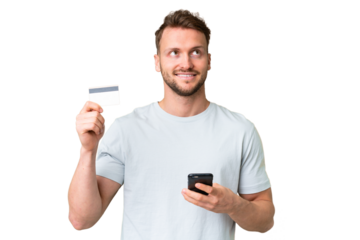 Young handsome caucasian man over isolated chroma key background buying with the mobile with a credit card while thinking