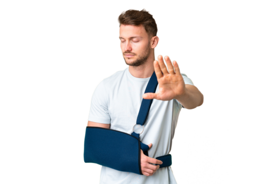 Young caucasian man with broken arm and wearing a sling over isolated chroma key background making stop gesture and disappointed
