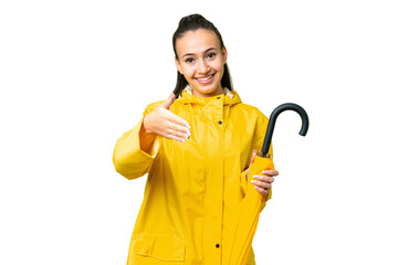 Young Arabian woman with rainproof coat and umbrella over isolated chroma key background shaking hands for closing a good deal