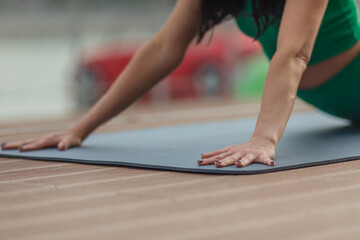 Close up of young woman flexing feet, stretching on yoga mat outdoors in summer