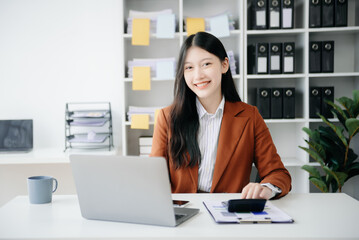 Fototapeta premium Young beautiful woman typing on tablet and laptop while sitting at the working wooden table office.