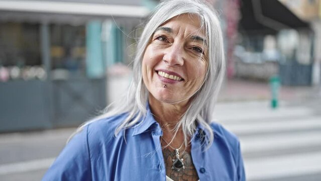 Middle age grey-haired woman smiling confident standing at coffee shop terrace