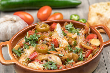 arabian food of Chicken in tomato paste with spicy pickles, tomatoes and almonds 