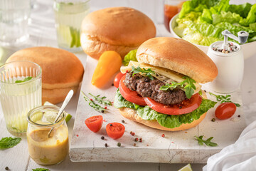 Tasty grilled hamburger served with lemonade and mustard.