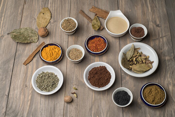 large collection of different spices and herbs on a wooden table 