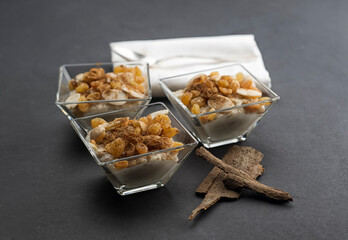 Delicious rice pudding with cinnamon in bowl, topped with almonds nuts and raisins