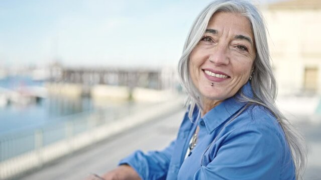 Middle age grey-haired woman smiling confident standing at seaside