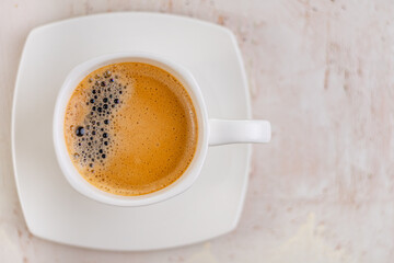 White cup of espresso on a light rustic background.