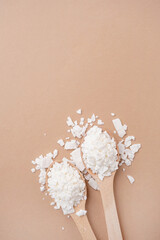 soy wax in wooden spoon on brown background, copy space
