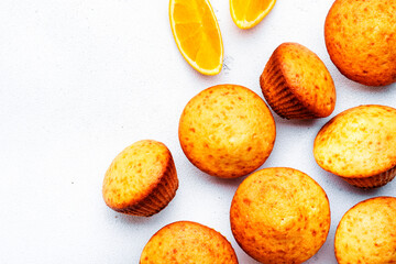 Sweet orange muffins on white table background, homemade pastries, top view, copy space