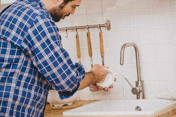 Man doing chores cleaning dishes cup at home kitchen sink holiday activity.