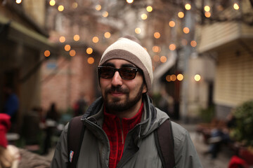 Bearded hipster man with a beret and sunglasses in front of a blurry background with light bulbs