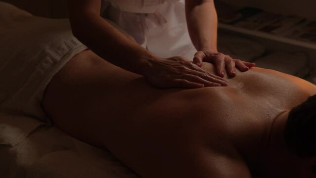 Spa, massage, cosmetology for men. Close-up of a handsome man's back having a full body massage at a men's spa.