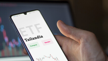An investor analyzing an etf fund. ETF text in Spanish : Thailand, buy, sell.