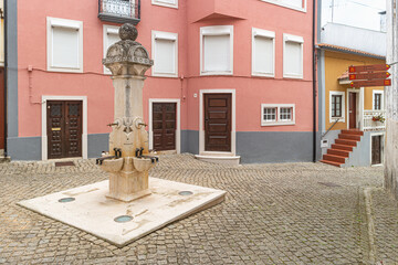 Stone pillory and fountain with old buildings in a square at Penacova, Portugal