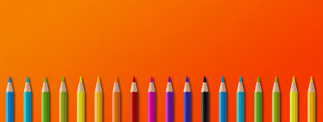 Colored pencil group isolated on orange. Panoramic banner background