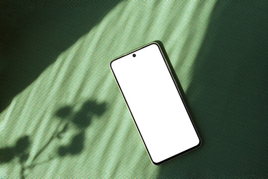 Minimalist summer business brand template, blank mobile phone screen mock up on bright green textile background with aesthetic floral sun light shadow, copy space